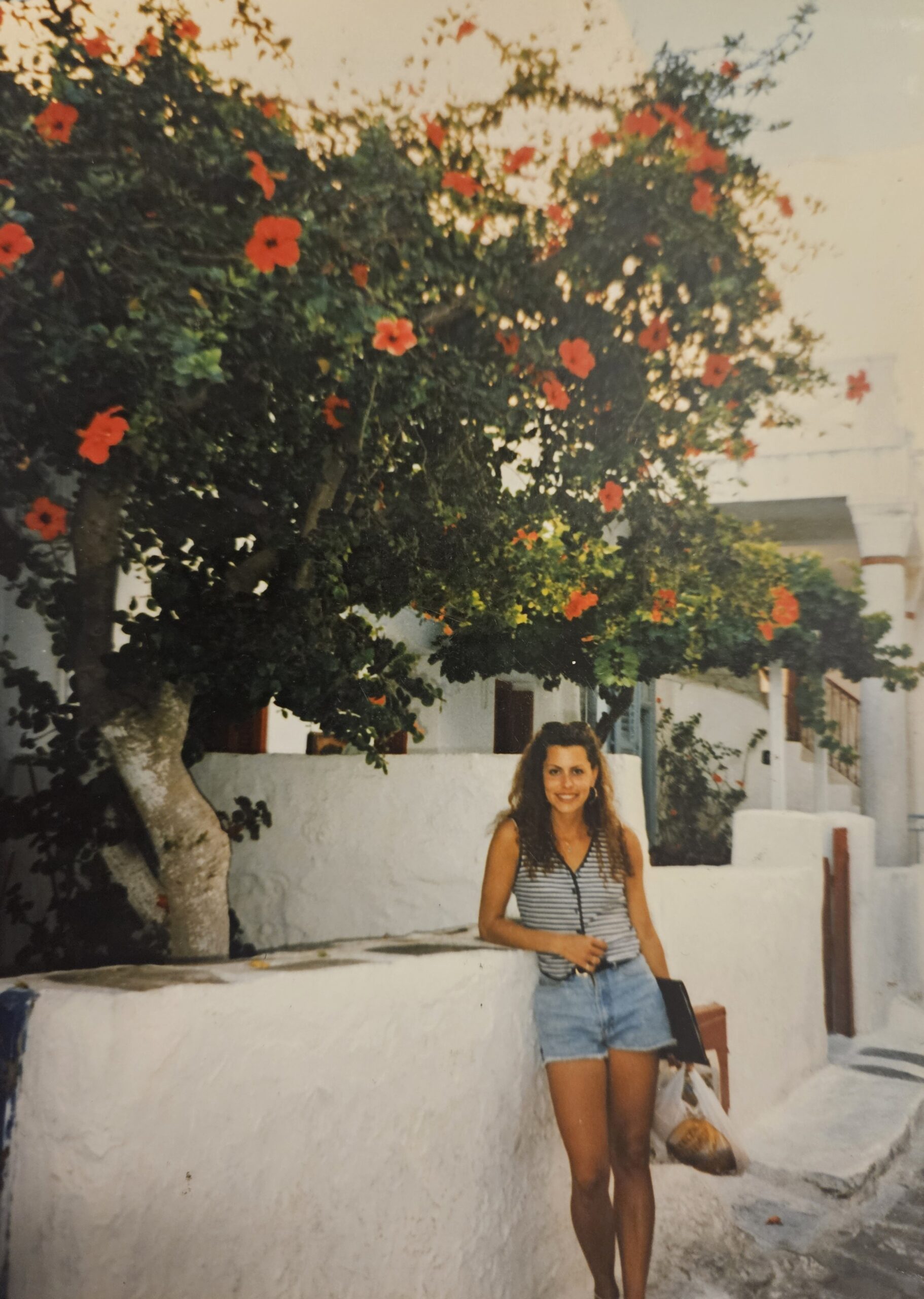 a woman standing in front of a whitewashed cement home on Mykonos island