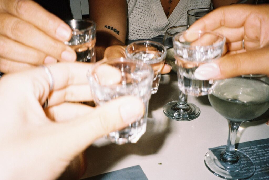 4 women clinking shot glasses of raki together over a dinner table in Crete
