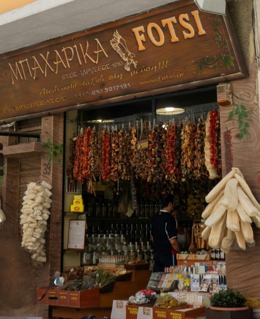 Store front of a Greek spice market with bins of spices and many hanging spices